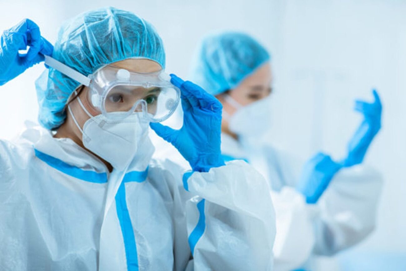 Image shows two healthcare workers in PPE.