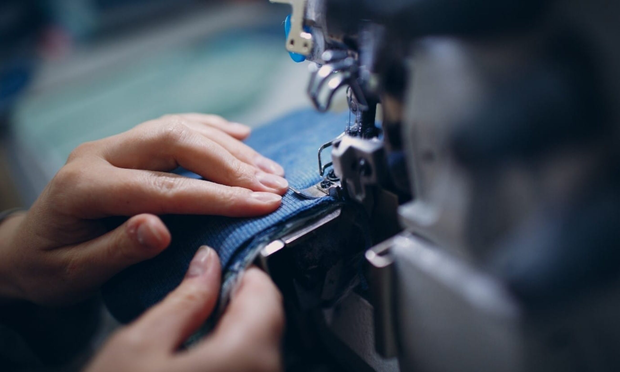 Image shows close up of hands sewing a garment using a machine.