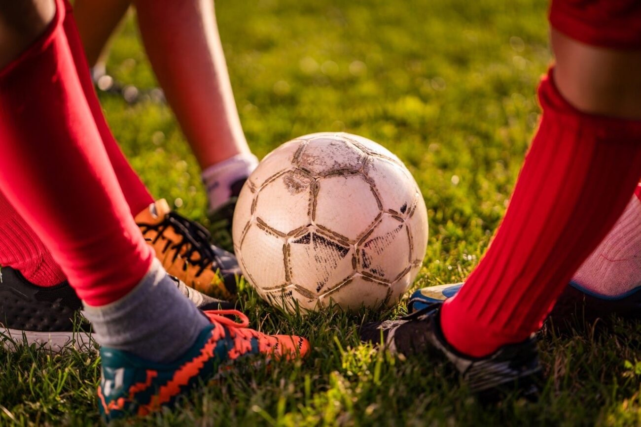 Image shows a close-up of three soccer players' legs and feet.